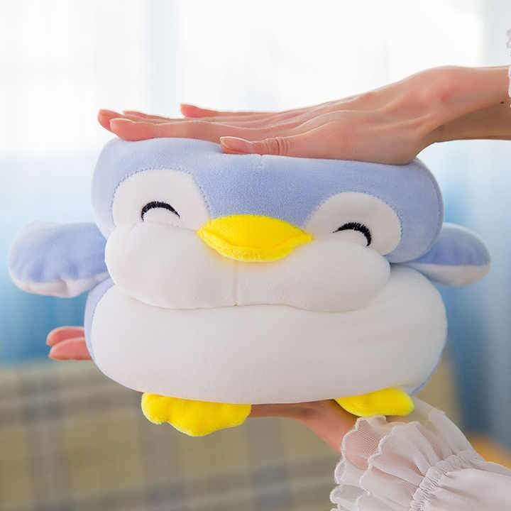Plush penguin toy held by a person with a blurred background